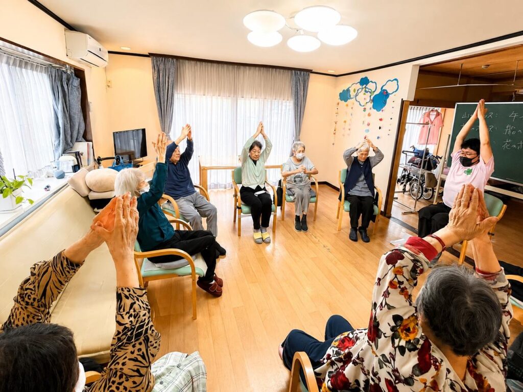 椅子に座ってヨガのポーズをとる利用者様たち シニアヨガ体操 大田区上池台 ファミリーケア心の家 上池台
