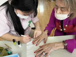 施術中：スタッフがご利用者様にネイルを施すネイルレクリエーション 大田区上池台のデイサービス ファミリーケア心の家 上池台