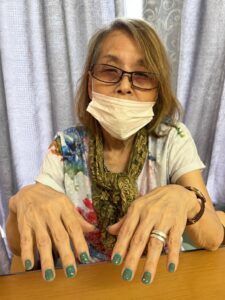 緑ネイル:緑に赤いドットのネイルを見せるご利用者様 おしゃれを楽しむ ファミリーケア心の家 上池台