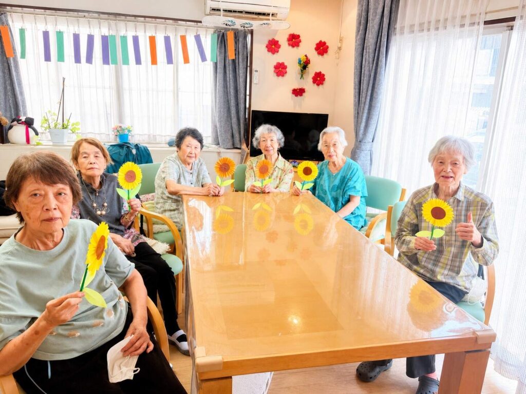完成した手作りのひまわりを手に笑顔の利用者様 夏の創作活動 大田区上池台のデイサービス ファミリーケア心の家 上池台